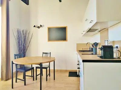 a kitchen with a table and chairs in a room at Grand studio lumineux au calme, centre historique in Pertuis