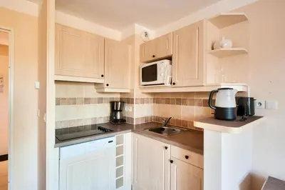 a kitchen with wooden cabinets and a microwave at Les Coteaux de Pont Royal en Provence - maeva Home - Maison climatisée 3 pièces 6 personnes - Sélection MAE-5714 in Mallemort