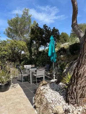 a patio with a table and a blue umbrella at Maison cottage en Provence, Spa & piscine, pour 4 personnes- Gîtes Les Estelles in Cavaillon