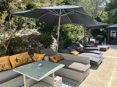 a group of couches and an umbrella on a patio at Maison cottage en Provence, Spa & piscine, pour 4 personnes- Gîtes Les Estelles in Cavaillon