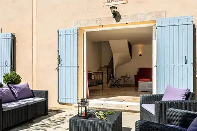 a patio with two wicker chairs and an open door at Mas Saint Julien in Cavaillon