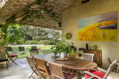 a patio with a wooden table and chairs at VillaOustal. Parc Arboré 4500 m2. Piscine chauffée. in Carpentras