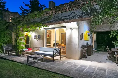 a patio with a couch and a table at VillaOustal. Parc Arboré 4500 m2. Piscine chauffée. in Carpentras