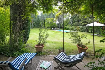 two chairs and a table in a yard with a pool at VillaOustal. Parc Arboré 4500 m2. Piscine chauffée. in Carpentras