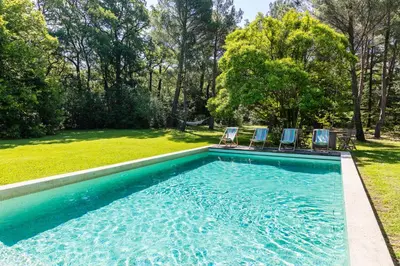 a swimming pool with two chairs and a yard at VillaOustal. Parc Arboré 4500 m2. Piscine chauffée. in Carpentras