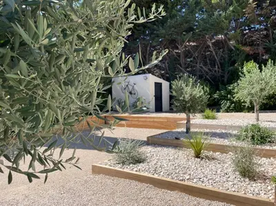a garden with trees and a small white building at LA VILLA 81 in Mormoiron