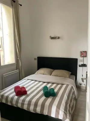 two slippers on a bed with a striped blanket at T3 centre ville Historique in Aix-en-Provence