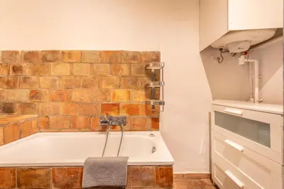 a bathroom with a bath tub next to a brick wall at Authentique Appartement Aixois in Aix-en-Provence