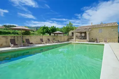 a swimming pool with chairs and a house at Authentique propriété in Bonnieux
