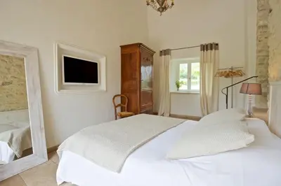 a bedroom with a white bed and a mirror at Authentique propriété in Bonnieux