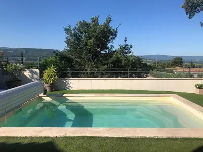 a swimming pool in the grass next to a wall at Villa Abelha en Provence in Apt
