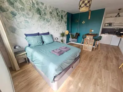 a bedroom with a bed with blue sheets and a kitchen at 104 Douce Provence au calme face à la piscine in Éguilles
