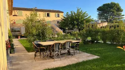 a wooden table and chairs in a garden at Domaine des Francobelges - Appartements in Lauris