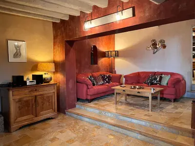 a living room with red couches and a table at La Paradisse – exceptional Provençal farmhouse (18th century) in Blauvac
