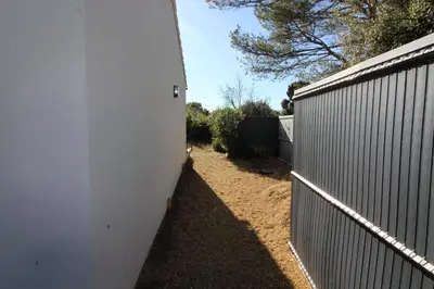 a fence next to a white wall next to a yard at Pause spa sur la route du Ventoux adults only in Carpentras