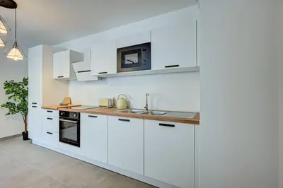 a white kitchen with white cabinets and a sink at Sublime Appartement 6 couchages avec Parking (Aix-en-Provence) in Aix-en-Provence