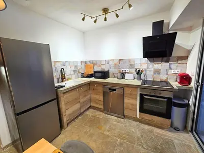 a kitchen with a stainless steel refrigerator and cabinets at Jacuzzi & Terrasse en bord de rivière in Fontaine-de-Vaucluse