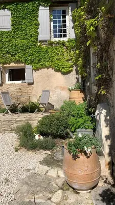 a cat laying next to a house with a large planter at le mas du lavoir in Gordes