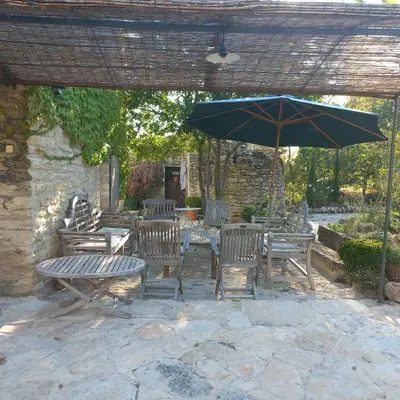 a patio with a table and chairs and an umbrella at le mas du lavoir in Gordes