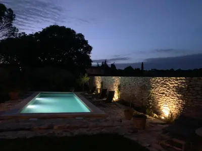 a swimming pool in a yard at night at le mas du lavoir in Gordes
