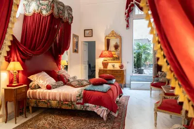 a bedroom with a bed with a red canopy at Appartement de luxe : Le Petit Trianon au coeur d'Aix-en-Provence in Aix-en-Provence