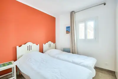 two beds in a bedroom with an orange wall at Village Pont Royal en Provence - maeva Home - Appartement climatisé 3 pièces 4 personnes avec terrasse aménagée - Prestige - super Home MAE-3084 in Mallemort