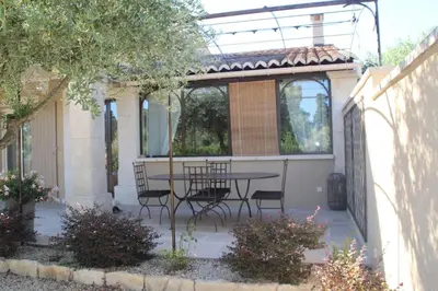 a patio with a table and chairs in a backyard at Lou Mas dou Souleou & Spa in Cheval-Blanc