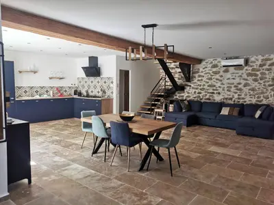 a dining room and living room with a table and chairs at Maison de la bonne fontaine. in Lauris