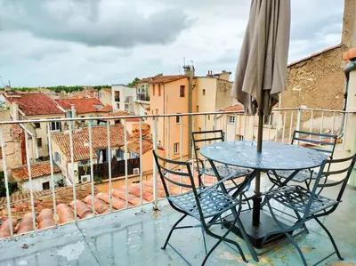 a table and chairs on a balcony with an umbrella at Superbe T3 avec terrasse en plein cœur du centre historique in Aix-en-Provence