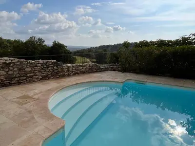 a swimming pool in a yard with a stone wall at La Petite Paradisse – mas provençal exceptionnel in Blauvac