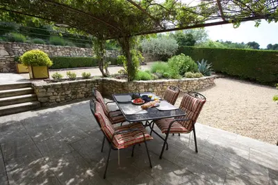 a table and chairs under a pergola in a garden at La Petite Paradisse – mas provençal exceptionnel in Blauvac