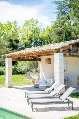 a patio with lounge chairs and a pavilion next to a pool at Villa des Alpilles in Eygalières