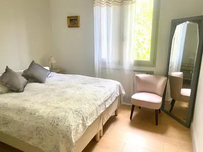 a bedroom with a bed and a chair and a mirror at Villa des Alpilles in Eygalières