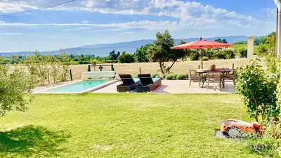 a garden with a table and an umbrella and a pool at La Belle Lumière in Saint-Saturnin-les-Apt