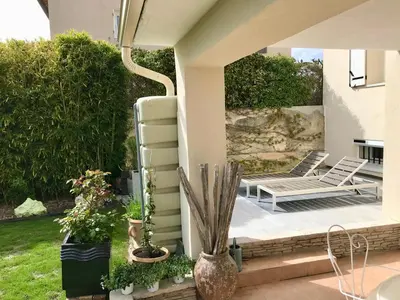 a patio with two lounge chairs and plants at Les 2 Oliviers in Caromb