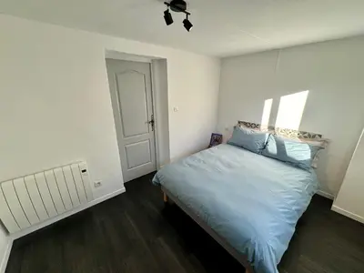 a bedroom with a bed with blue sheets and a door at Les 2 Oliviers in Caromb