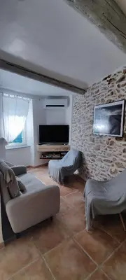 a living room with a couch and a tv on a brick wall at Latipik in Lançon-Provence