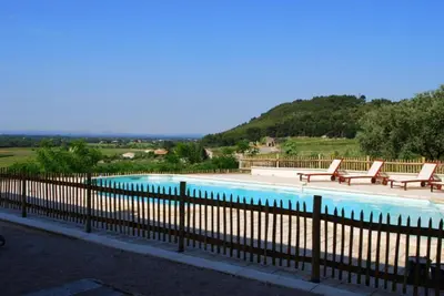 a swimming pool with two benches and a fence at Masmazan in Mazan