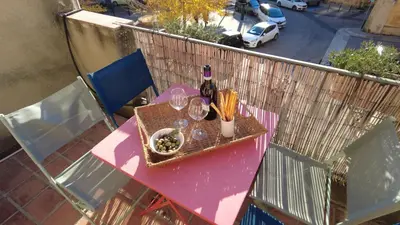 a pink table with wine bottles and glasses on a balcony at Lovely house teracce and parking in historic center in Aix-en-Provence