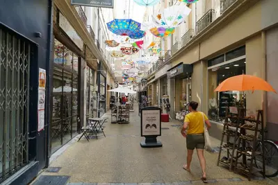 a man walking down a street with an orange umbrella at La Petite Maison des Boettes in Carpentras