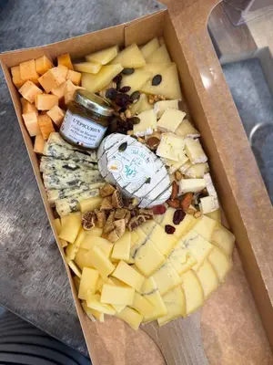 a box filled with different types of cheese and a jar at Chambre d hôte gite Au fond du jardin in Saint-Saturnin-lès-Avignon
