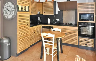 a kitchen with a wooden table and a clock on the wall at La Villa Des Songes in Pernes-les-Fontaines
