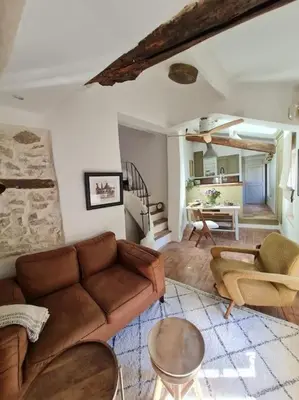 a living room with a couch and a table at Appartement avec terrasse sur les toits classé 5* in LʼIsle-sur-la-Sorgue
