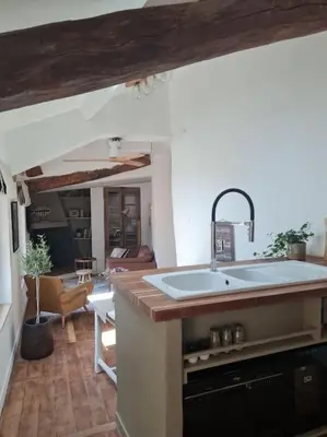 a kitchen with a sink and a living room at Appartement avec terrasse sur les toits classé 5* in LʼIsle-sur-la-Sorgue