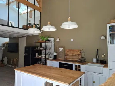 a kitchen with white cabinets and a counter with lights at Le Mas du Castellas 5* in Le Thor