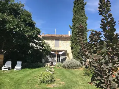 a house with two white chairs in a yard at Les Tarraïettes au pied du Luberon in Lourmarin