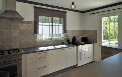 a large kitchen with white cabinets and a microwave at Zèbre in Eyragues