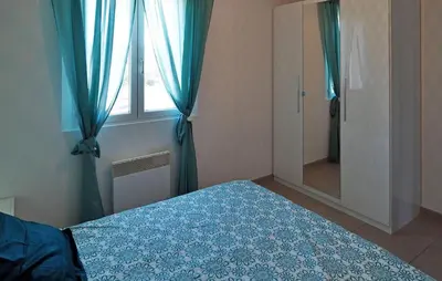a bedroom with a bed and a window with blue curtains at Zèbre in Eyragues