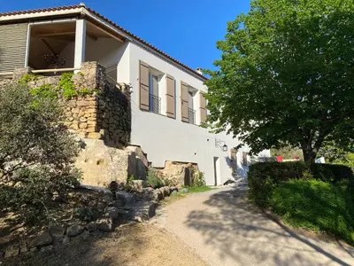 a house with a stone wall and a tree in front of it at LA BASTIDETTE PROVENçALE in Jouques