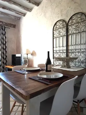 a dining room with a wooden table with two glasses of wine at Appartement en campagne au coeur du luberon in Roussillon